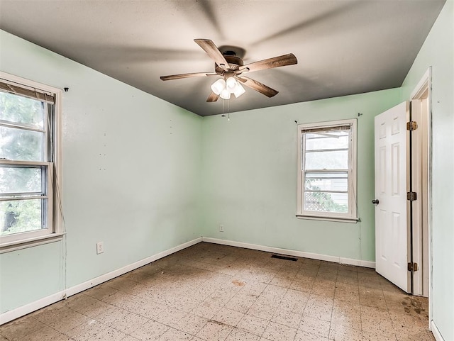 empty room featuring baseboards, ceiling fan, and visible vents
