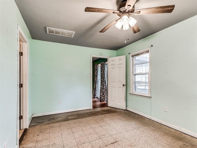 spare room featuring baseboards, ceiling fan, and visible vents