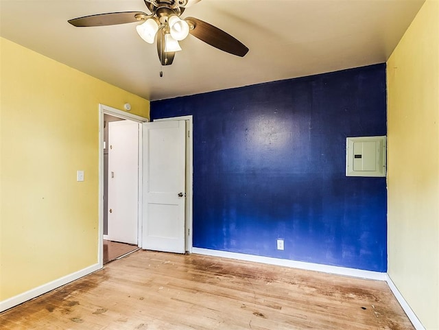 unfurnished room featuring baseboards, ceiling fan, electric panel, and wood finished floors