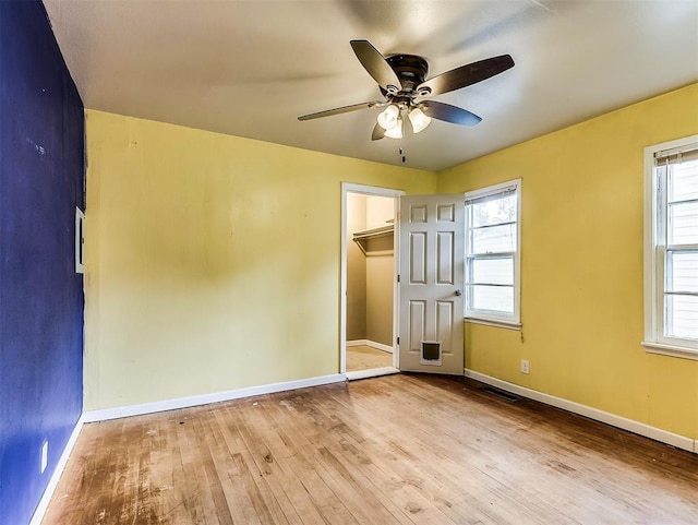 unfurnished bedroom with wood-type flooring, baseboards, visible vents, and multiple windows
