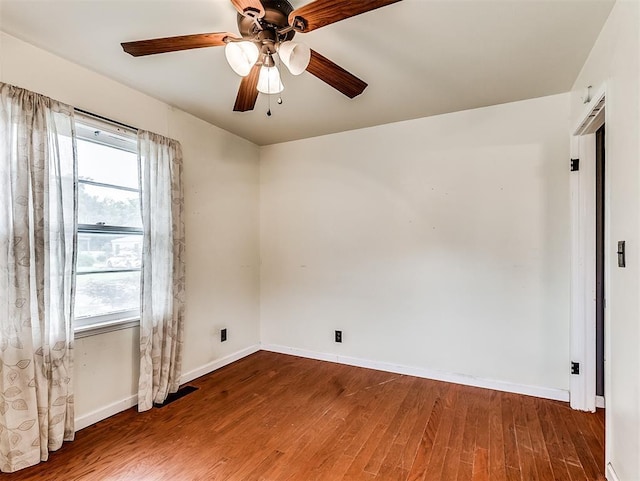 empty room with baseboards, a ceiling fan, wood finished floors, and a wealth of natural light