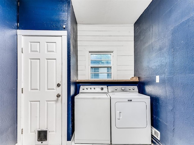 clothes washing area featuring washing machine and clothes dryer, laundry area, and a textured wall