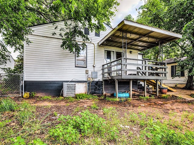 rear view of property featuring fence, cooling unit, and a deck