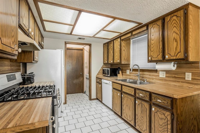 kitchen featuring decorative backsplash, under cabinet range hood, a sink, appliances with stainless steel finishes, and light tile patterned floors