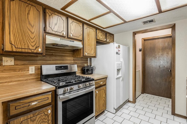 kitchen with light countertops, white fridge with ice dispenser, gas range, under cabinet range hood, and visible vents