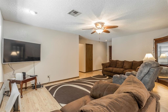 living area with visible vents, a textured ceiling, ceiling fan, and light wood-type flooring