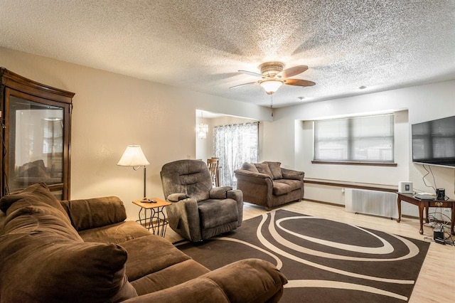 living room with a textured ceiling, ceiling fan, and wood finished floors