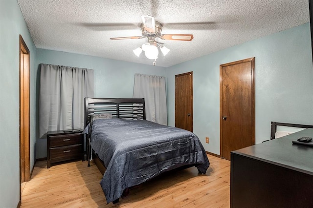 bedroom with light wood-style floors, a ceiling fan, two closets, and a textured ceiling
