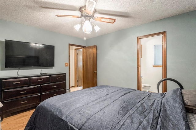 bedroom featuring light wood-type flooring, a textured ceiling, ceiling fan, and ensuite bath