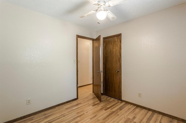 spare room with light wood-style floors, a textured ceiling, baseboards, and ceiling fan