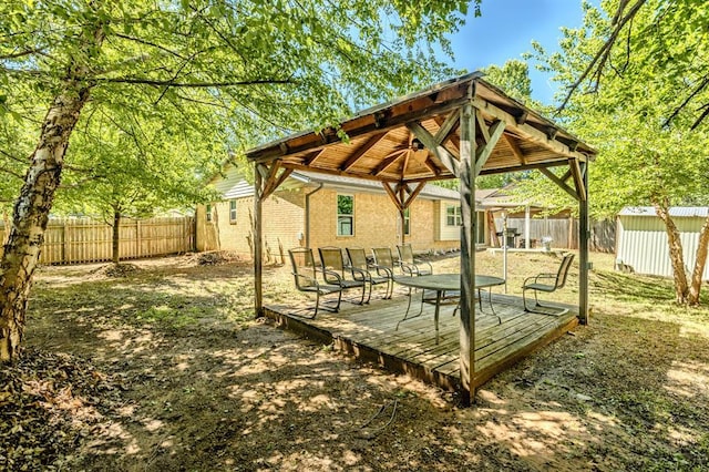 view of yard with a deck, a gazebo, an outdoor structure, a fenced backyard, and a storage unit