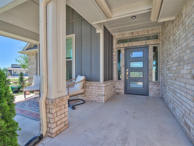 property entrance featuring board and batten siding, a porch, and brick siding