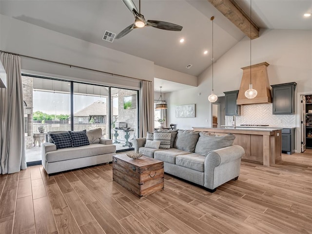 living room with light wood-style floors, high vaulted ceiling, a ceiling fan, beamed ceiling, and visible vents