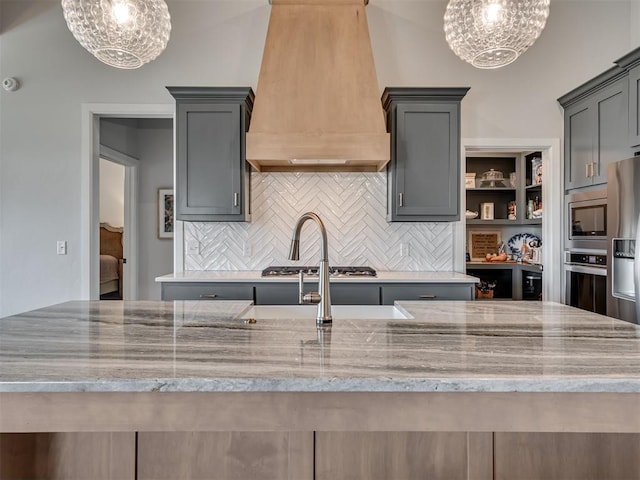 kitchen with premium range hood, tasteful backsplash, light stone countertops, and a notable chandelier