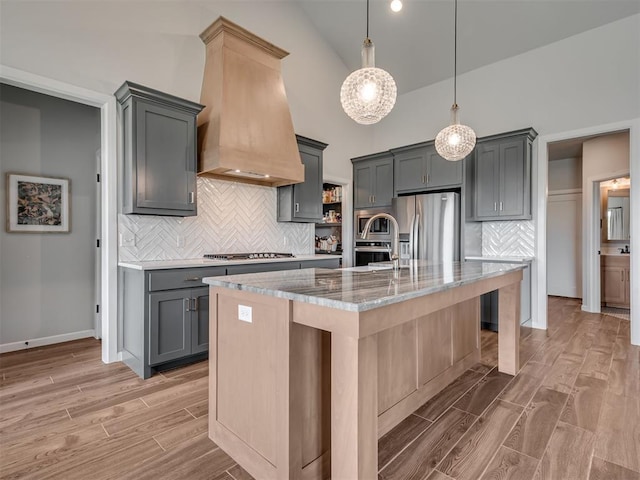 kitchen with stainless steel appliances, gray cabinetry, custom exhaust hood, and wood tiled floor