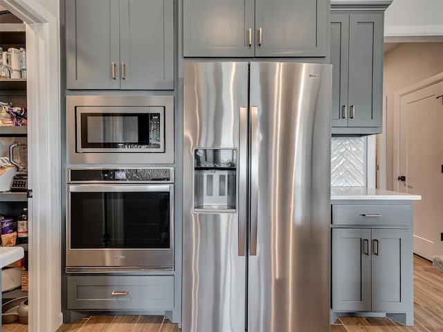 kitchen with light countertops, light wood-style flooring, gray cabinetry, and stainless steel appliances