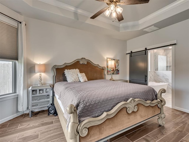 bedroom featuring crown molding, a tray ceiling, a barn door, and wood finished floors