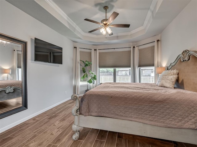 bedroom featuring crown molding, a raised ceiling, baseboards, and wood finished floors