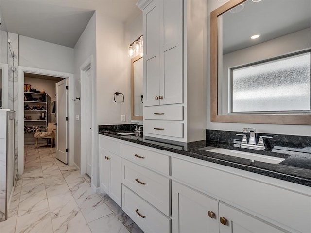 full bath with double vanity, a sink, marble finish floor, and a spacious closet