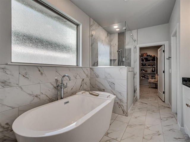 bathroom featuring a walk in closet, plenty of natural light, and a stall shower