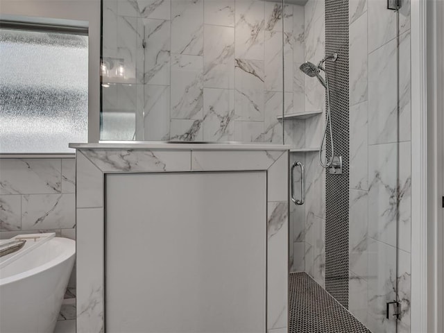 full bathroom featuring marble finish floor, tile walls, a freestanding bath, a marble finish shower, and a wealth of natural light