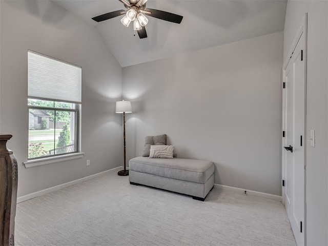 living area with baseboards, ceiling fan, light carpet, and lofted ceiling