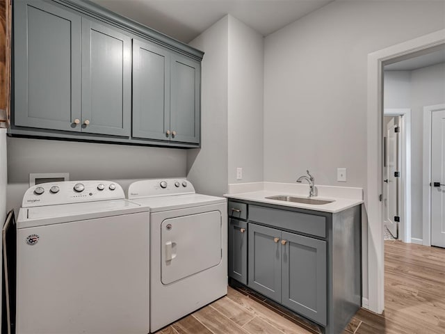 washroom featuring light wood-type flooring, a sink, cabinet space, and washing machine and clothes dryer