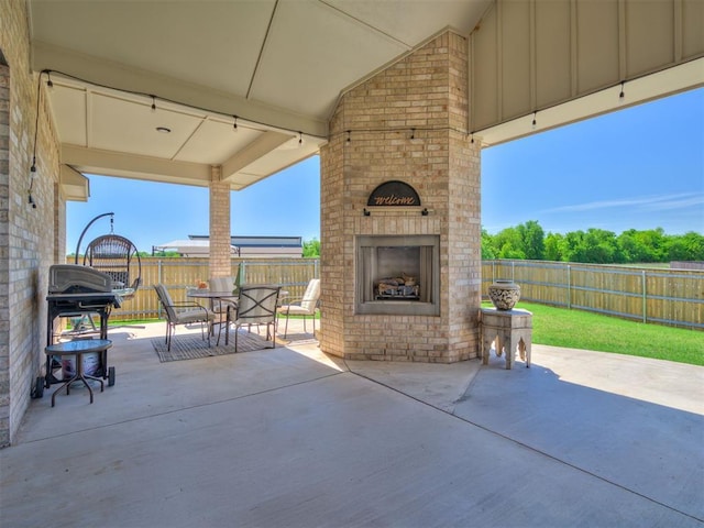 view of patio with a fenced backyard, an outdoor brick fireplace, and outdoor dining space