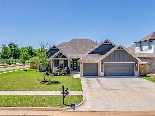 craftsman house featuring board and batten siding, driveway, a front yard, fence, and an attached garage