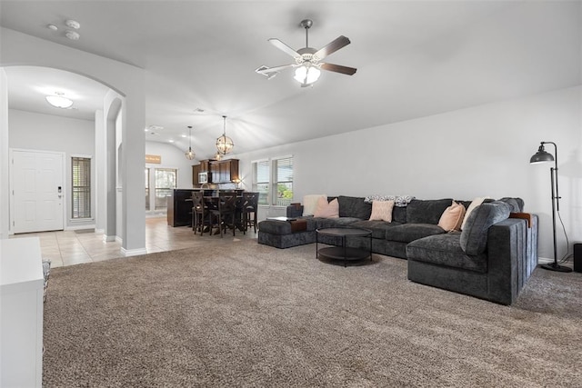 living area featuring light tile patterned flooring, light carpet, arched walkways, a ceiling fan, and lofted ceiling