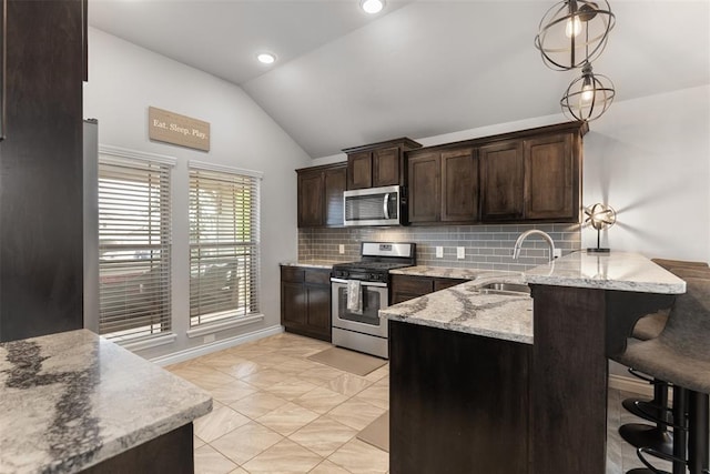 kitchen with dark brown cabinetry, backsplash, a sink, lofted ceiling, and stainless steel appliances