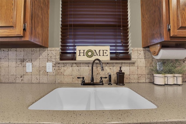 107 Chuckwagon Way, Elk City, OK 73644 - room details featuring backsplash, light stone counters, brown cabinetry, and a sink