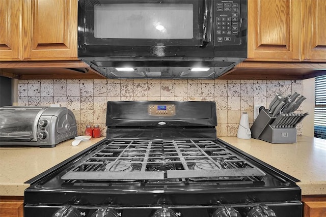 107 Chuckwagon Way, Elk City, OK 73644 - kitchen with brown cabinets, decorative backsplash, black appliances, and a toaster