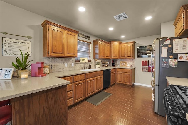 107 Chuckwagon Way, Elk City, OK 73644 - kitchen with visible vents, brown cabinetry, tasteful backsplash, a sink, and black appliances