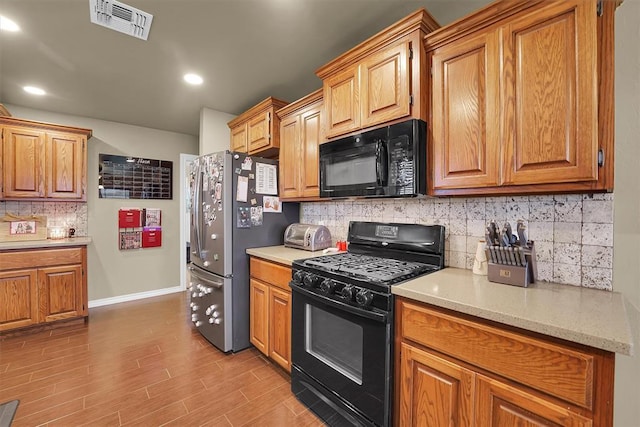 107 Chuckwagon Way, Elk City, OK 73644 - kitchen featuring visible vents, decorative backsplash, baseboards, light wood finished floors, and black appliances