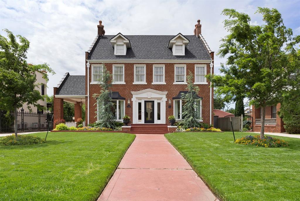 georgian-style home with a front lawn, fence, and a chimney
