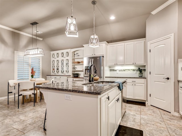 kitchen featuring stainless steel fridge, a sink, a kitchen island with sink, decorative backsplash, and lofted ceiling