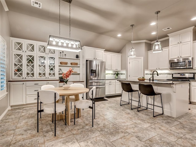 kitchen featuring tasteful backsplash, stainless steel appliances, white cabinetry, and visible vents