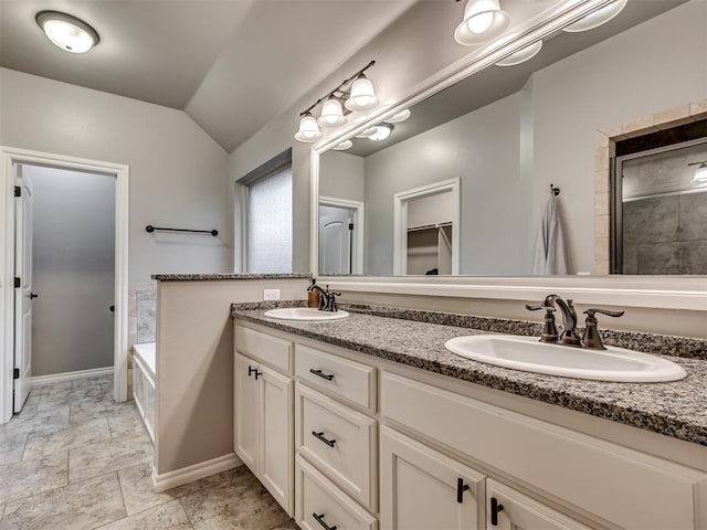 full bath featuring baseboards, a sink, lofted ceiling, and double vanity