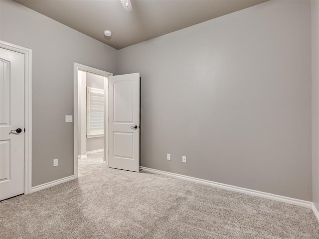 unfurnished bedroom with baseboards and light colored carpet