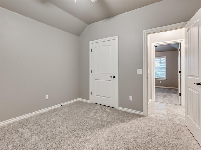 unfurnished bedroom with baseboards, carpet, and lofted ceiling