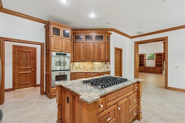 12700 Jabez Rd, Edmond, OK 73013 - kitchen featuring appliances with stainless steel finishes, decorative backsplash, brown cabinetry, light stone counters, and crown molding