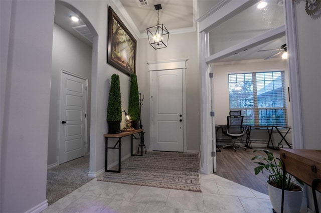 entryway featuring baseboards, light carpet, a ceiling fan, arched walkways, and light tile patterned floors