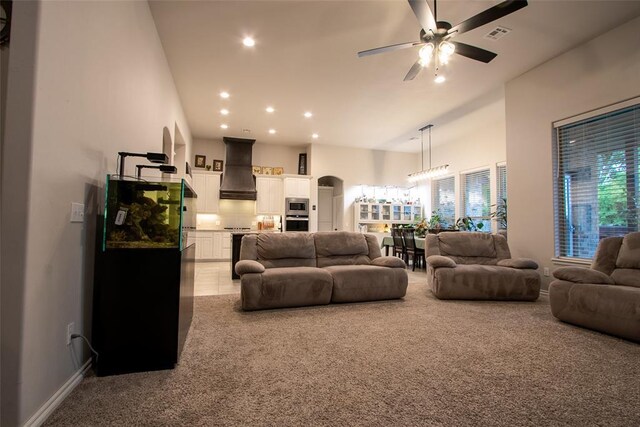 living area featuring ceiling fan, carpet, recessed lighting, baseboards, and a high ceiling