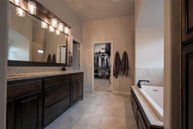 bathroom with baseboards, a walk in closet, vanity, and a garden tub