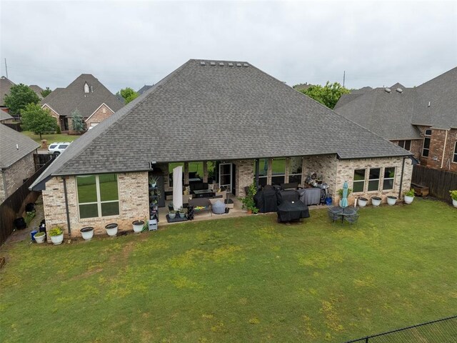 back of house featuring a patio area, roof with shingles, brick siding, and a hot tub