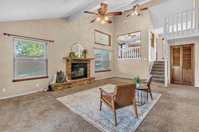carpeted living area with ceiling fan, beam ceiling, a fireplace, baseboards, and stairway
