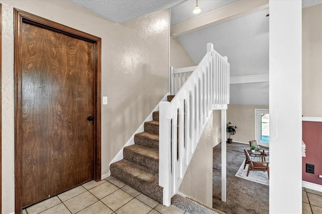 tiled entrance foyer with baseboards, a textured ceiling, and vaulted ceiling