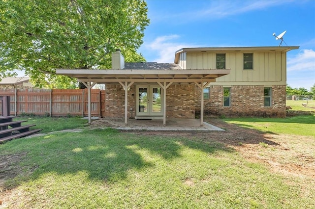 back of property featuring french doors, a chimney, a yard, and brick siding