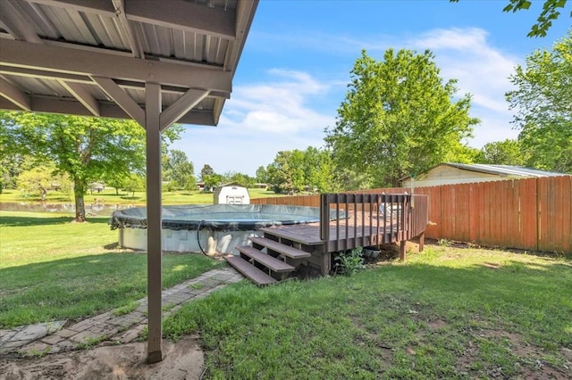view of yard with fence, a wooden deck, and a covered pool